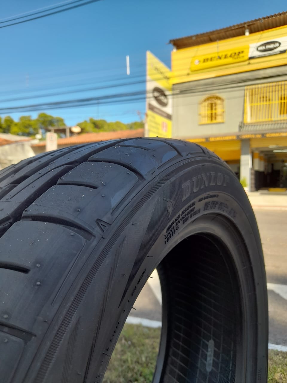 Pneu Dunlop em destaque com a fachada da WIX PNEUS ao fundo